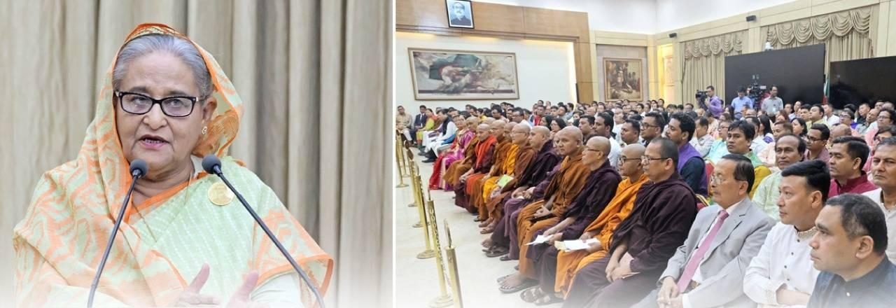 Sheikh Hasina speaking at a podium beside a gathering of religious leaders